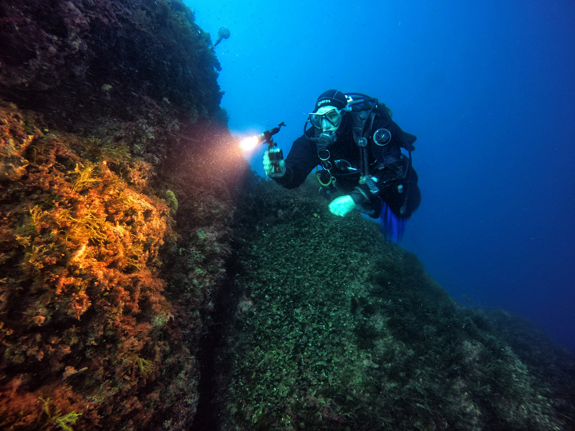 The rocks in this picture appear mostly blue-green, but where the diver’s light shines we can see the true colours emerging.